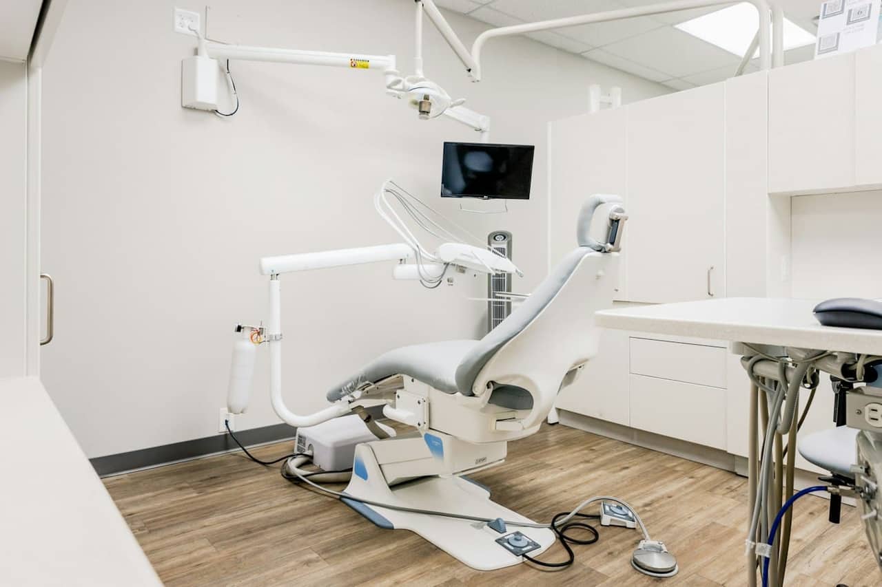 A calm, light-filled treatment room with a dental chair and warm wooden floor